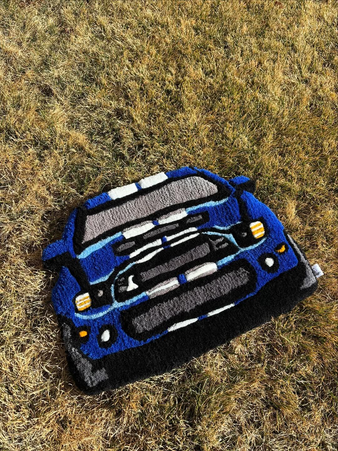 Hand-tufted blue rally car rug shown front-on, laid out on grass