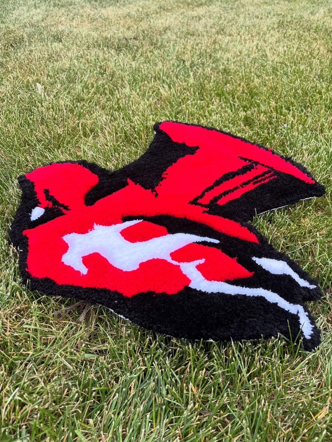 Hand-tufted rug of a caped figure in bold red, black and white
