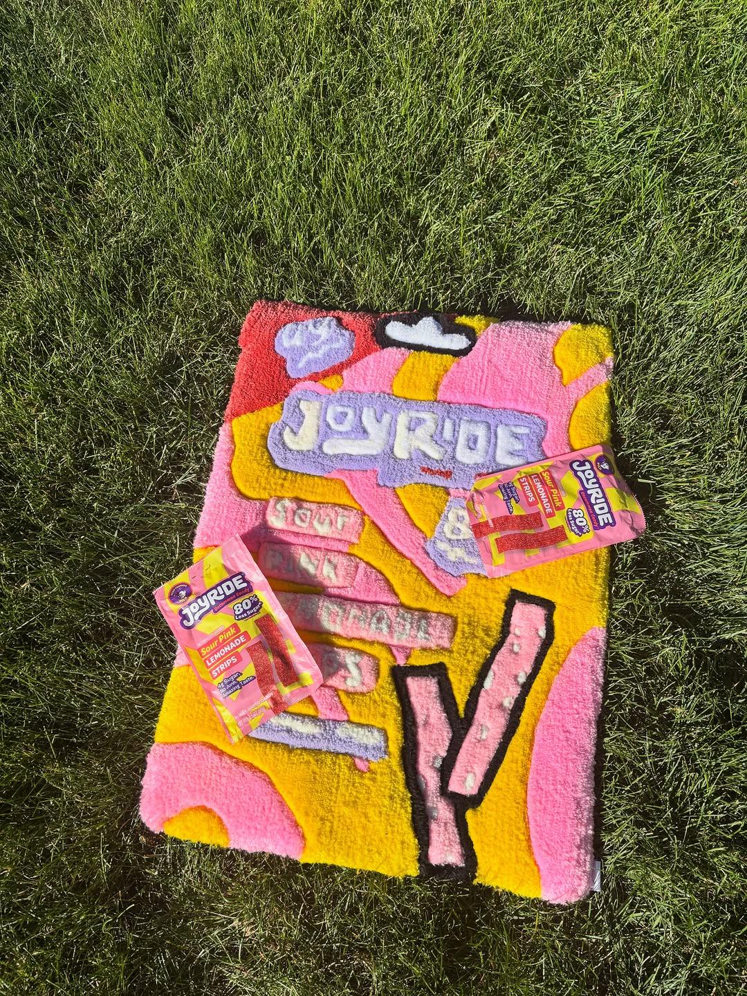 Hand-tufted rug in pink and yellow with sweets arranged on top of it
