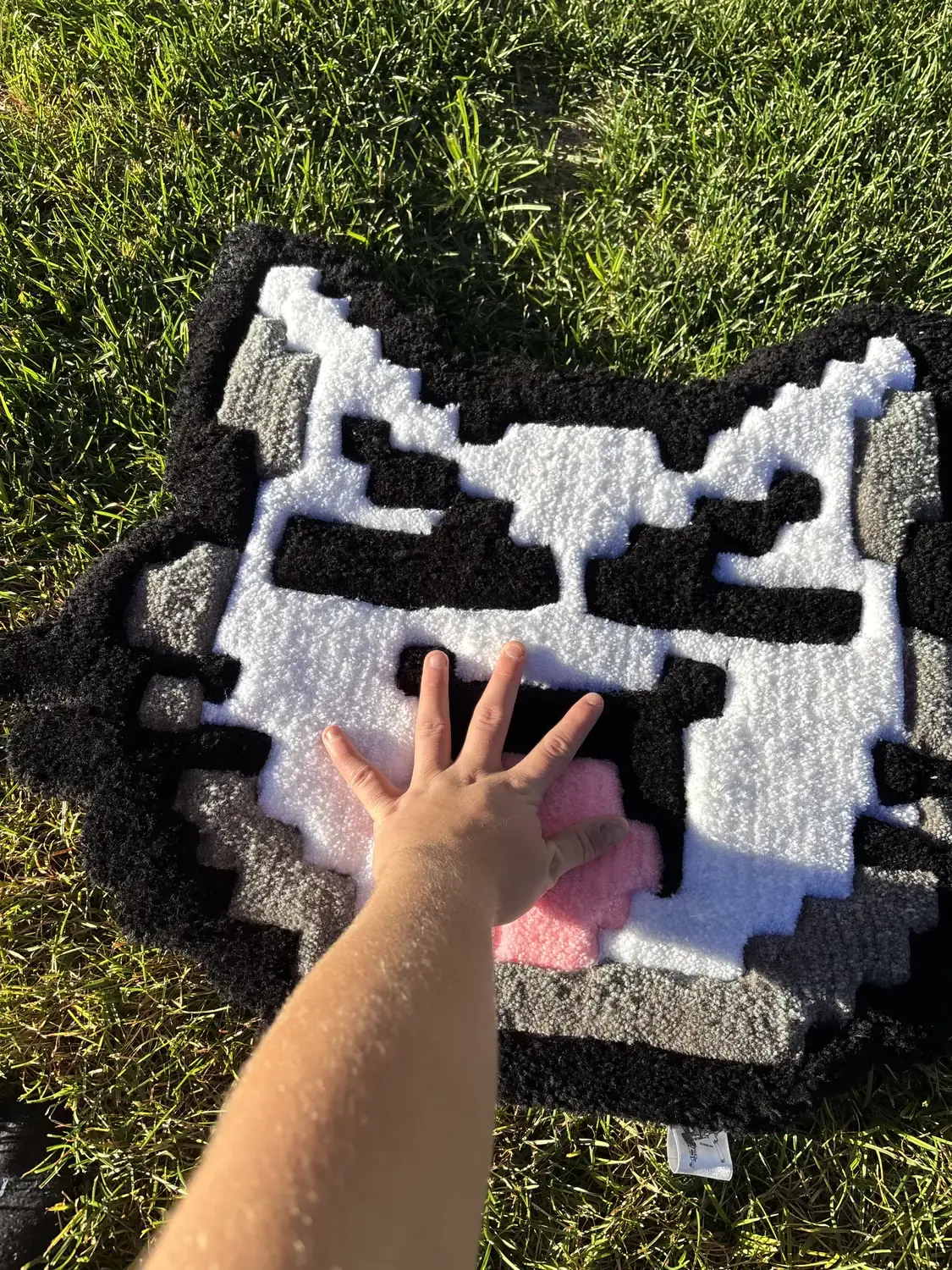 A hand resting on the thick pile of the cat face rug