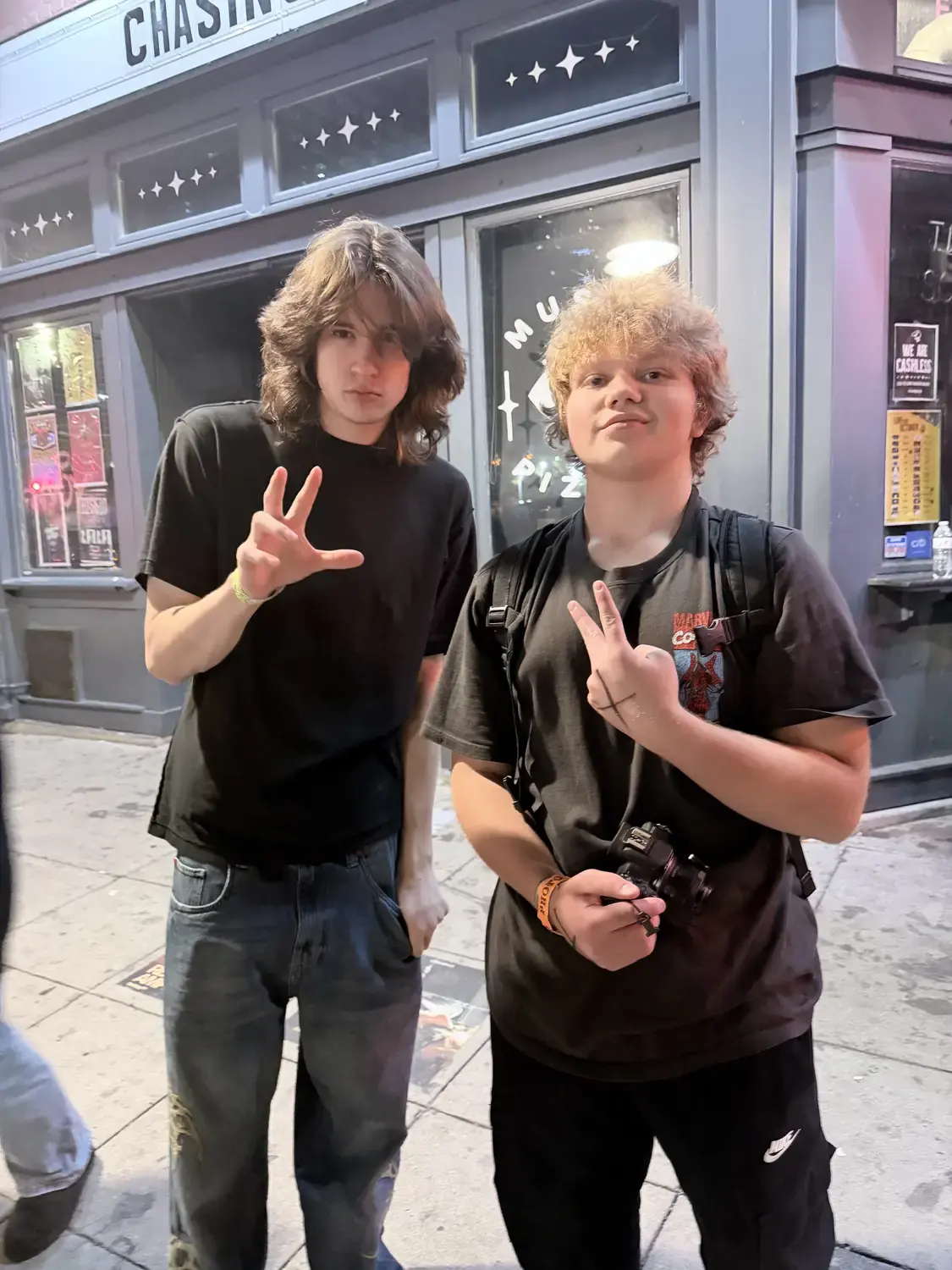Two people posing together outside a music venue at night