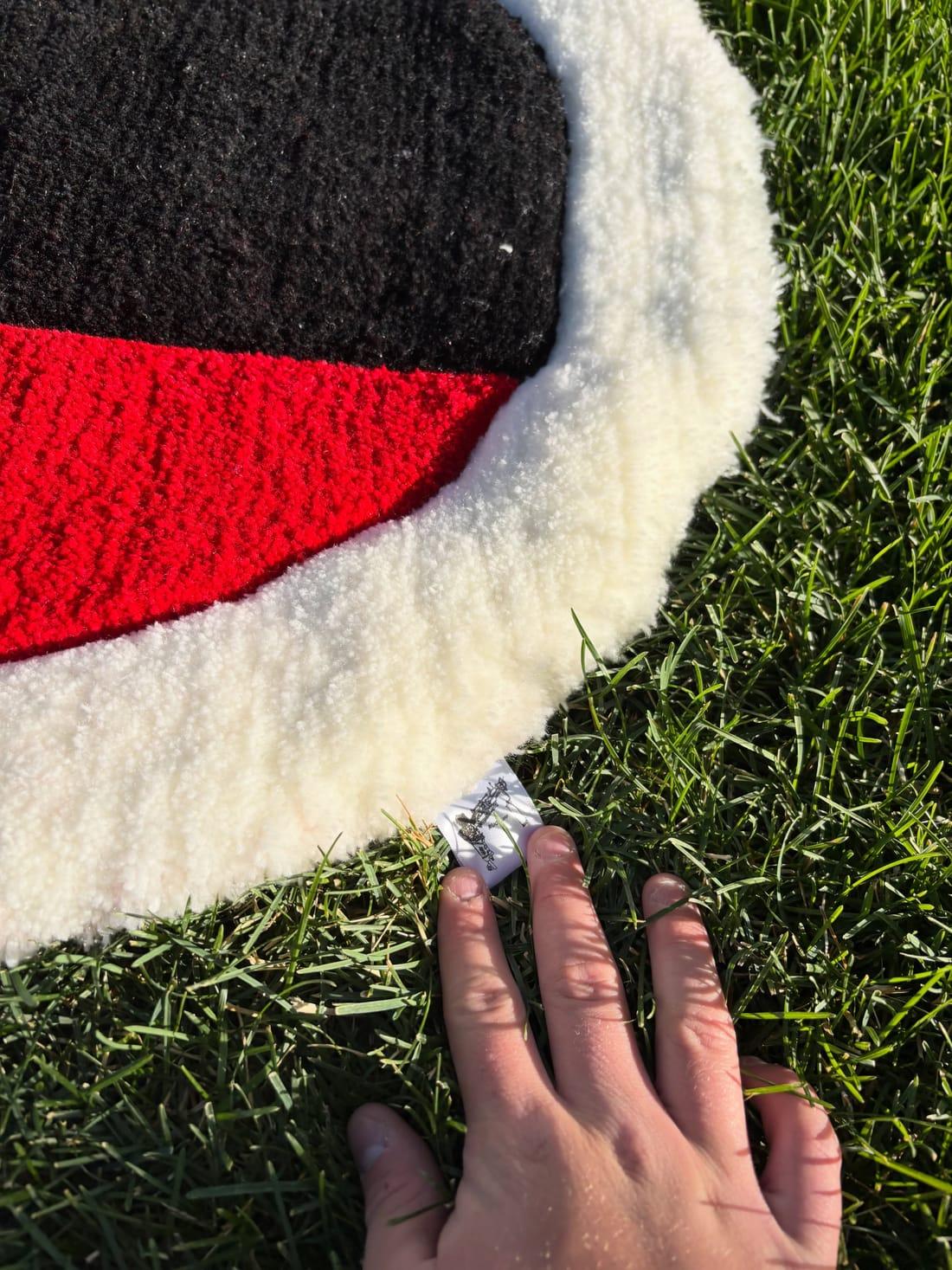 A hand resting on the rug's white pile edge beside the woven RugRuff label