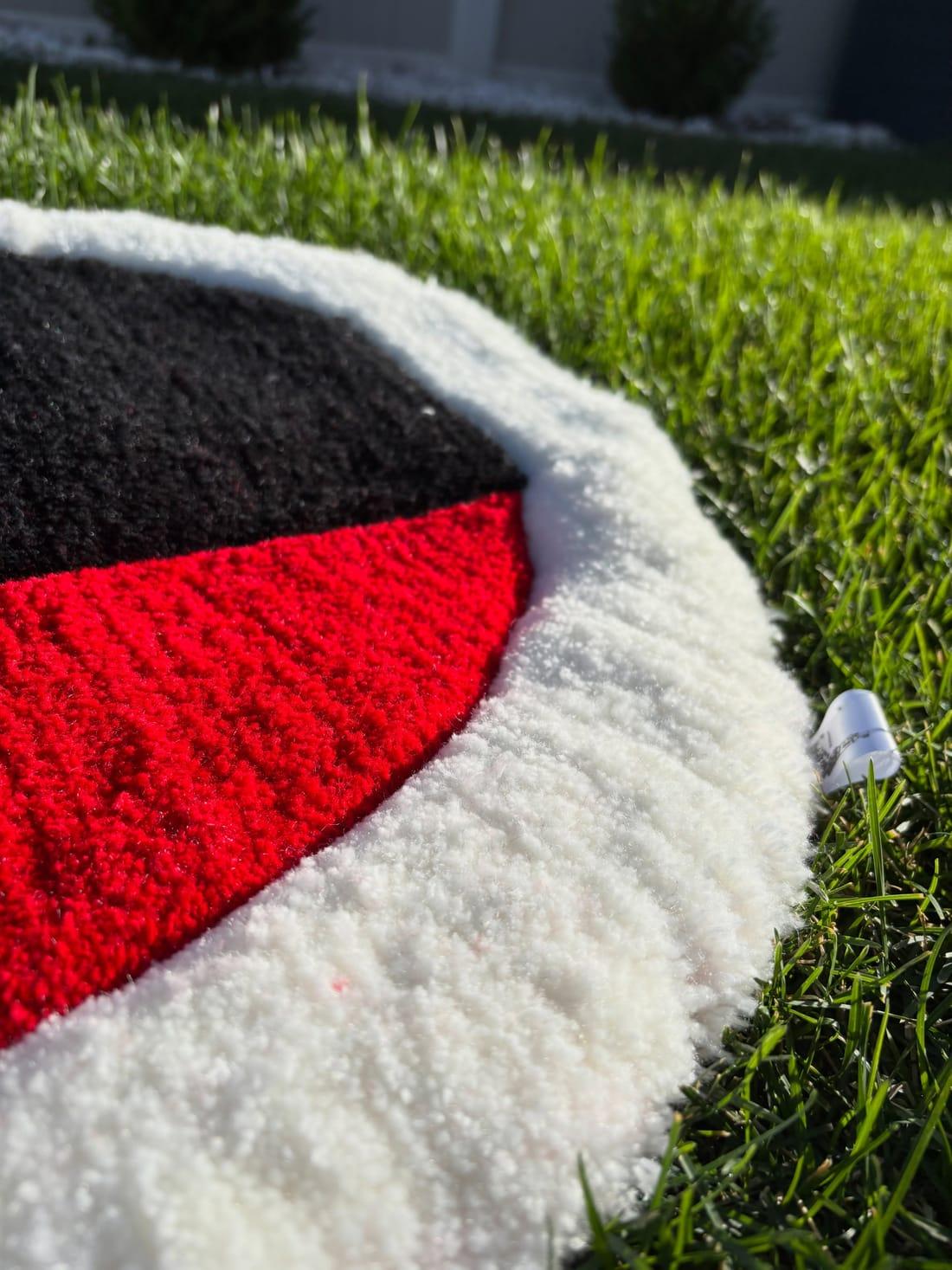 Close-up of the rug's thick white pile edge against the red and black tufting