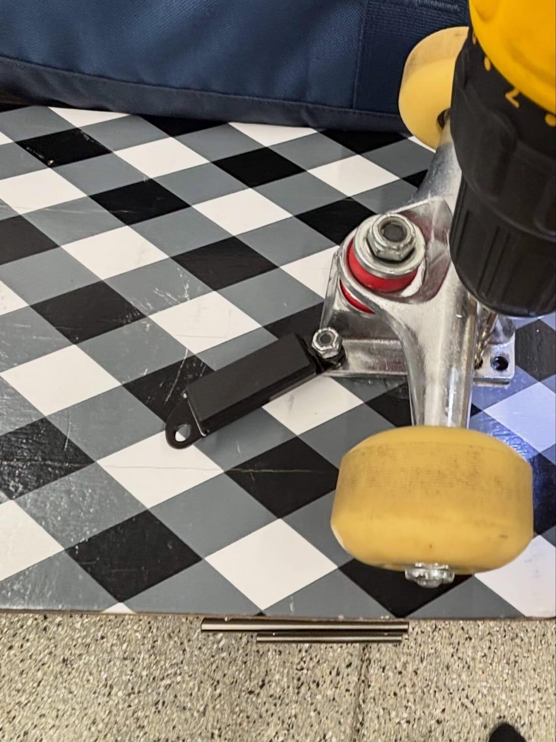 The Skategrounds sensor bolted under a skateboard truck baseplate on a chequered deck